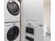 Stacked white washer and dryer beside a bathroom door with a step stool at 361 17Th St # 2120, Atlanta, GA 30363
