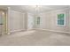 Spacious bedroom with neutral carpet, base-molding, and two windows with treed views at 1183 Woods Ne Cir, Atlanta, GA 30324