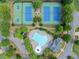 Aerial view featuring tennis and basketball courts with a pool surrounded by trees at 1450 Liberty Ln, Cumming, GA 30040