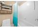 Functional bathroom featuring a shower-tub combo, white tiled walls, and a practical storage shelf at 1450 Liberty Ln, Cumming, GA 30040