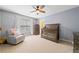 Calm Bedroom with gray walls, a rocking chair, and a crib, illuminated by a ceiling fan with light at 1450 Liberty Ln, Cumming, GA 30040