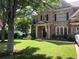 Beautiful brick two-story home featuring a well-manicured front yard with lush green grass and mature shade trees at 1450 Liberty Ln, Cumming, GA 30040