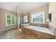 Bright bathroom boasts a glass shower and a soaking tub with tiled surround and natural light from two windows at 1450 Liberty Ln, Cumming, GA 30040