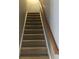 Carpeted staircase featuring a wooden handrail, providing a safe and elegant transition between floors at 1450 Liberty Ln, Cumming, GA 30040