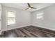 Bright bedroom featuring modern ceiling fan, two windows, and stylish dark wood flooring at 1749 W Caribaea Se Trl, Atlanta, GA 30316