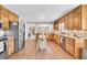 Open-concept kitchen with wood cabinets, stainless appliances, island, and tile floor at 3574 Timberloch Trl, Snellville, GA 30039