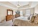A main bedroom featuring a tray ceiling, ceiling fan, and two windows at 3574 Timberloch Trl, Snellville, GA 30039