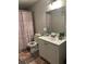 Well-lit bathroom features a white vanity, toilet, mirror, shower with snowflake curtain, and gray wood-look flooring at 2351 Carver Nw Dr, Atlanta, GA 30314