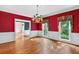 Formal dining room with hardwood floors, a decorative chandelier, and bright red walls with elegant wainscoting at 3185 Country Club Nw Ct, Kennesaw, GA 30144