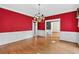 Formal dining room with hardwood floors, decorative chandelier, and elegant wainscoting with bright red walls at 3185 Country Club Nw Ct, Kennesaw, GA 30144
