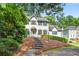 Beautiful home with a manicured lawn, mature trees, and a charming covered entryway leading to the front door at 3185 Country Club Nw Ct, Kennesaw, GA 30144