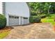 Exterior shot featuring a two-car garage with a concrete driveway, landscaping, and green foliage at 3185 Country Club Nw Ct, Kennesaw, GA 30144