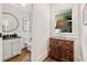 Elegant bathroom with a round mirror, patterned wallpaper, and a rustic wooden cabinet with a table lamp at 54 Camden Ne Rd, Atlanta, GA 30309