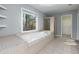 Large soaking tub in bathroom featuring tiled floor, shower, and a large window offering private outdoor views at 2001 Towne Lake W Hls, Woodstock, GA 30189