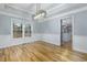 Light-filled dining room with hardwood floors, white wainscoting, modern light fixture and large window at 2001 Towne Lake W Hls, Woodstock, GA 30189