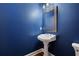 Powder room features dark blue walls, a pedestal sink, and hardwood floors at 1121 Vinings Grove Se Way, Smyrna, GA 30082