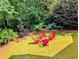 Well-manicured backyard featuring bright red Adirondack chairs around a small outdoor table for entertaining at 3803 Upland Dr, Marietta, GA 30066
