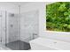 Modern bathroom features a glass shower, soaking tub, and a view of nature at 5264 Prestley Crossing Ln, Douglasville, GA 30135