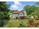 View of a home's back exterior showcasing a spacious yard with a covered patio and fire pit at 1925 Waters Ferry Dr, Lawrenceville, GA 30043