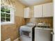 Functional laundry room with tile flooring, ample storage cabinets, and modern washer and dryer units at 1925 Waters Ferry Dr, Lawrenceville, GA 30043
