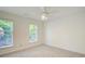 Well-lit bedroom showcasing neutral walls, carpet, a ceiling fan, and large windows offering a pleasant view at 202 Garden Ct, Atlanta, GA 30328