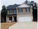 Charming two-story home featuring a two-car garage, neutral siding, and black shutters on a cloudy day at 30 Barton Ln, Covington, GA 30016