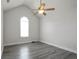 This bedroom features wood flooring, white walls, a ceiling fan, and a uniquely shaped window at 2682 Field Spring Dr, Lithonia, GA 30058