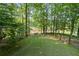 Lush green backyard with mature trees, a fence, and a view of the surrounding landscape at 3525 Stone Cliff Way, Woodstock, GA 30189