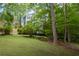 Lush backyard with mature trees, green lawn, and natural fence for privacy at 3525 Stone Cliff Way, Woodstock, GA 30189