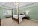 Spacious primary bedroom featuring a four-poster bed, tray ceiling, and bright windows at 3525 Stone Cliff Way, Woodstock, GA 30189