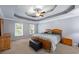 Main bedroom featuring tray ceilings, windows, and neutral carpet flooring at 2196 Kildare Nw Way, Kennesaw, GA 30152