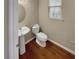 Cozy powder room featuring a pedestal sink, toilet, wood flooring, and a window for natural light at 265 Edinburgh Ln, Woodstock, GA 30188