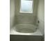 Bathroom bathtub area featuring modern tile and a window for natural light at 3378 English Elm Way, Loganville, GA 30052