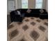 Living room featuring a large black sectional sofa on a patterned rug at 3378 English Elm Way, Loganville, GA 30052