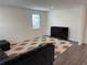 Minimalist living room featuring a comfortable dark sofa, patterned rug, and a sleek television at 3378 English Elm Way, Loganville, GA 30052