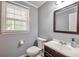 Cozy half bathroom features a modern vanity, mirror, and a window with natural light at 2165 Shillings Chase Nw Dr, Kennesaw, GA 30152