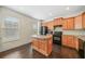 Well-lit kitchen featuring an island, wood cabinets, black appliances, and hardwood floors at 262 Bell Grove Ln, Suwanee, GA 30024