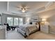 This main bedroom features a tray ceiling, ceiling fan, and large windows that provide ample natural light at 5357 Harbury Cv, Suwanee, GA 30024