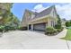 A three car garage showing an expansive driveway and manicured landscaping at 5357 Harbury Cv, Suwanee, GA 30024