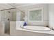 Beautiful bathroom featuring a glass shower enclosure and luxurious soaking tub beneath a bright window at 10 Nesbit Reserve Ct, Atlanta, GA 30350