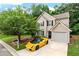 Two-story home featuring a tan exterior, black shutters, manicured lawn and a striking yellow luxury car in the driveway at 248 Springbottom Dr, Lawrenceville, GA 30046
