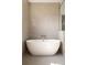 Modern soaking tub with wall-mounted faucet, set against a backdrop of textured beige tile at 555 Orme Ne Cir, Atlanta, GA 30306