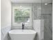 Bright bathroom features a freestanding tub and marble style tiled shower behind glass doors at 5399 Emily Cir, Ellenwood, GA 30294