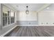 Bright living room featuring a large window and modern lighting fixture, complemented by sleek gray wood flooring at 5399 Emily Cir, Ellenwood, GA 30294