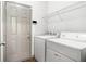 Bright laundry room with white washer and dryer, shelving, and neutral walls at 876 Ivydale Ln # 63, Lawrenceville, GA 30045
