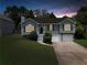 Charming split-level home featuring a manicured lawn, a two-car garage, and inviting curb appeal against a twilight sky at 4255 Brandy Ann Dr, Acworth, GA 30101
