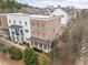 Aerial view of three-story brick townhome with a covered front porch, manicured landscaping, and neighborhood view at 2026 Forte Lane, Alpharetta, GA 30009