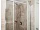 Shower with glass door, stone-look tile surround, and an adjustable shower head at 2026 Forte Lane, Alpharetta, GA 30009