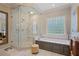 Bright bathroom featuring a glass enclosed shower, soaking tub with marble surround, and contemporary finishes at 515 Saint Barbaras Nw Ln, Marietta, GA 30064