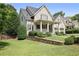 Well-maintained home exterior featuring lush lawn, stone retaining wall, and a welcoming front porch with mature trees at 515 Saint Barbaras Nw Ln, Marietta, GA 30064